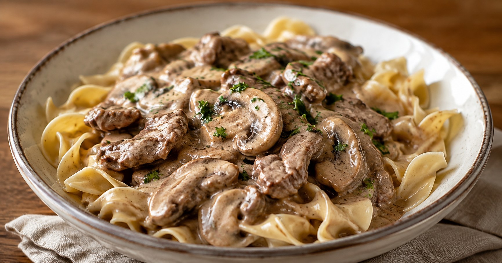 薄切り牛肉ときのこをクリーミーなソースで煮込み、麺にかけたビーフストロガノフ